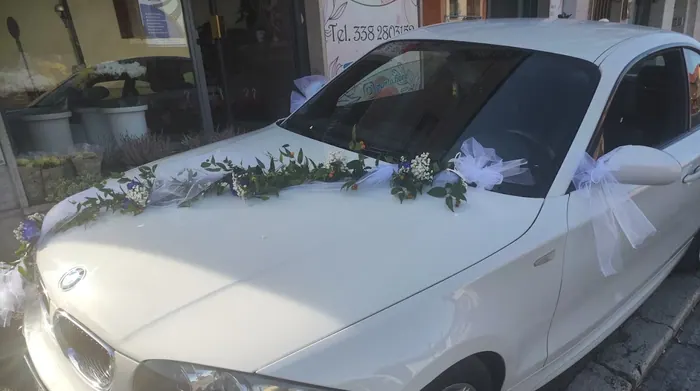 Auto bianca decorata con ghirlanda floreale e tulle per una cerimonia