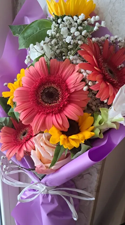 Bouquet con gerbere corallo, girasoli e gypsophila in carta lilla