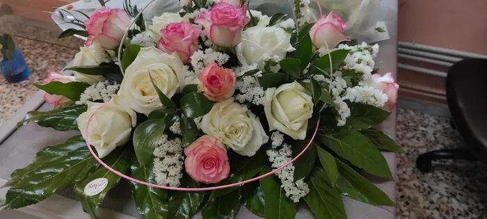 Composizione di rose bianche e rosa con statice bianco e foglie verdi