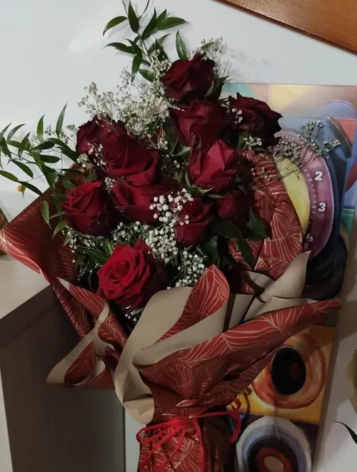 Mazzo di rose rosse con gypsophila in carta bordeaux