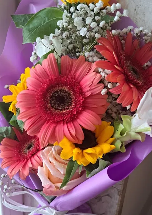 Bouquet con gerbere corallo, girasoli e gypsophila in carta lilla