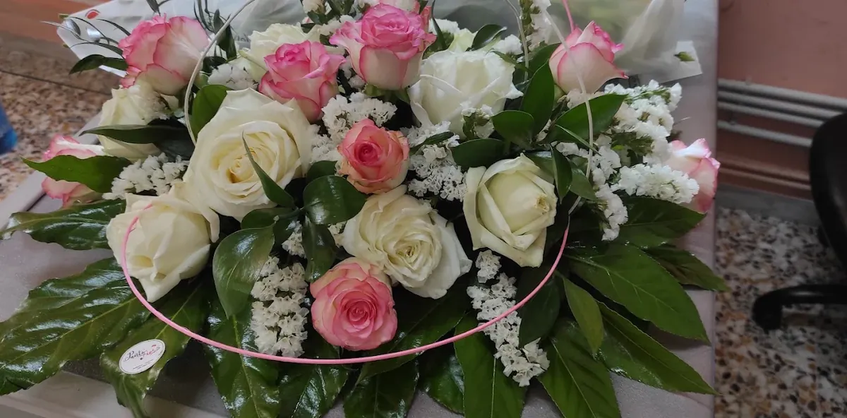 Composizione di rose bianche e rosa con statice e foglie verdi