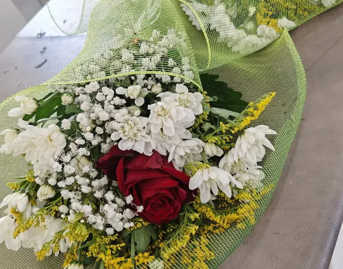 Bouquet bianco con una rosa rossa, margherite e gypsophila avvolto in rete verde