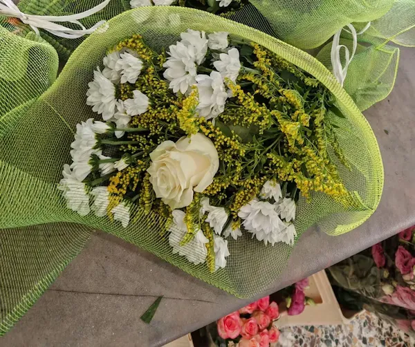 Bouquet di rose bianche e margherite in preparazione sul banco